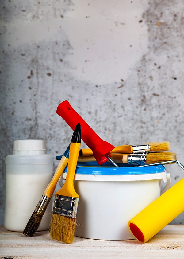 Paint can, roller and brush on the table. Items for home or office renovation on gray background.